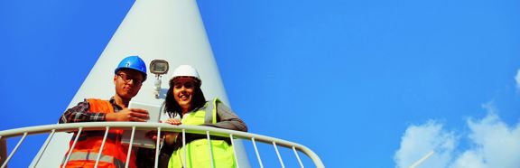 Twee technici met helm en veiligheidshesje bij een windturbine