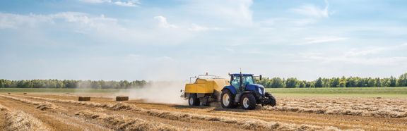 Tractor met balenpers op een geoogst graanveld